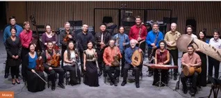 Fotografía de grupo de la Orquesta Intercultural de Vancouver, con sus integrantes y sus instrumentos en un escenario.